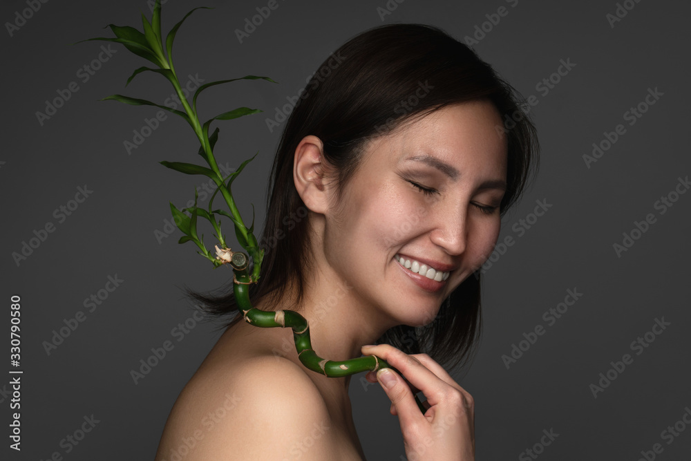 Beautiful asian woman with a bamboo plant in her hands Beautiful asian woman with a bamboo plant in her hands