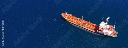 Aerial drone ultra wide top down photo of industrial LPG gas tanker ship cruising in low speed near Asian industrial plant