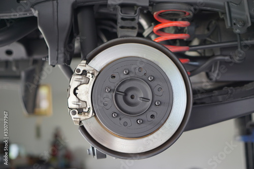 Disc brake of the vehicle for repair, in process of new tire replacement. Car brake repairing in garage.Selective focus disc brake on car, in process of new tire replacement.Close up.