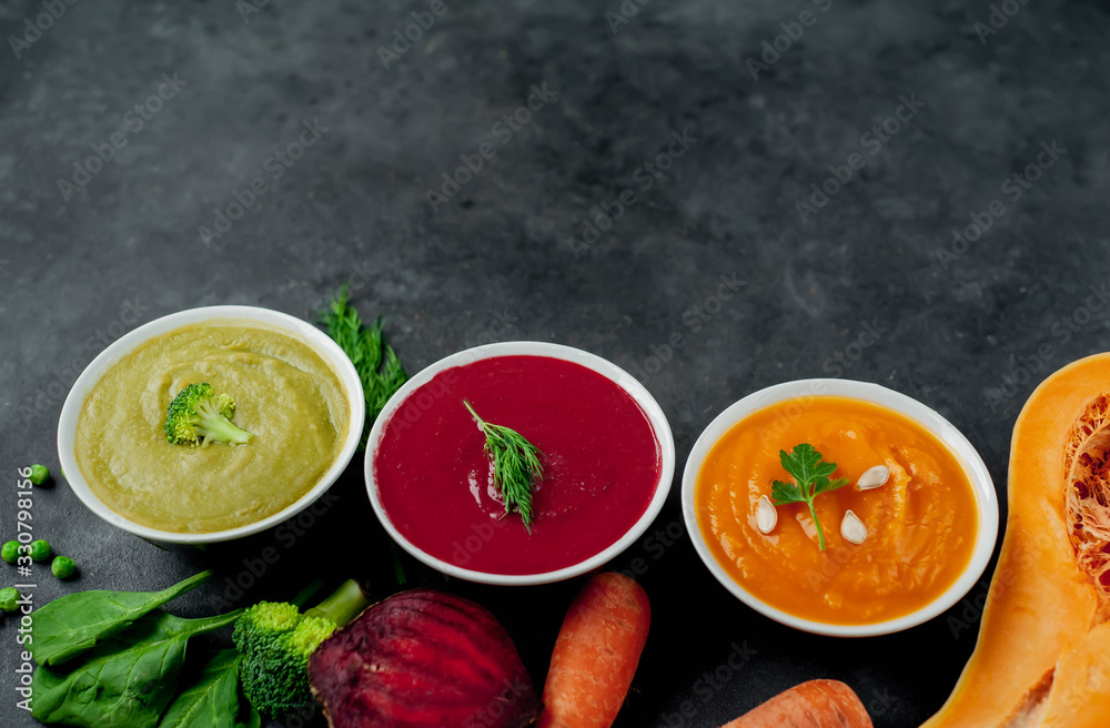 Set of vegetable soups. Broccoli, spinach, green peas soup. Pumpkin and carrot soup. Beetroot and carrot soup on a stone background with copy space for your text Set of vegetable soups. Broccoli, spinach, green peas soup. Pumpkin and carrot soup. Beetroot and carrot soup on a stone background with copy space for your text