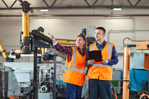 Male and Female Industrial Engineers Have Discussion while Using Tablet. They Work in a Industry Factory.