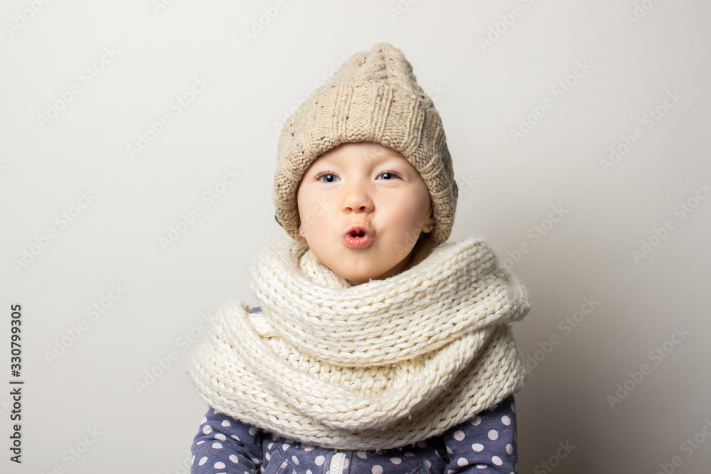 beautiful little baby in a hat is surprised on a light background. Concept of children's emotions, winter, shopping