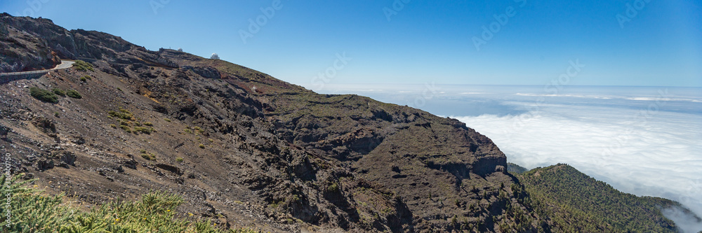 Aerial view of the National Park Caldera de Taburiente, volcanic crater seen from mountain peak of Mirador de Los Andenes Viewpoint. El Hierro on horizon line above the clouds. La Palma, Spain