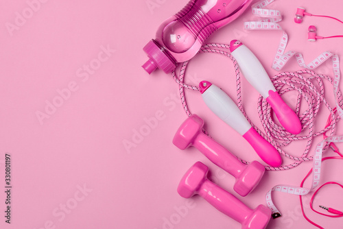 Fitness accesories, headphones and measure tape on pink background