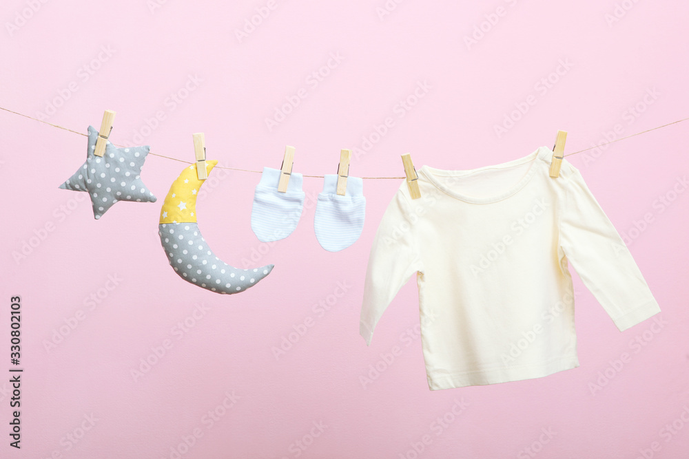Baby clothes on a rope on a colored background. The concept of washing baby clothes. Baby clothes on a rope on a colored background. The concept of washing baby clothes.