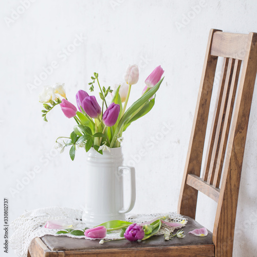 spring flowers on old chair on background old white wall