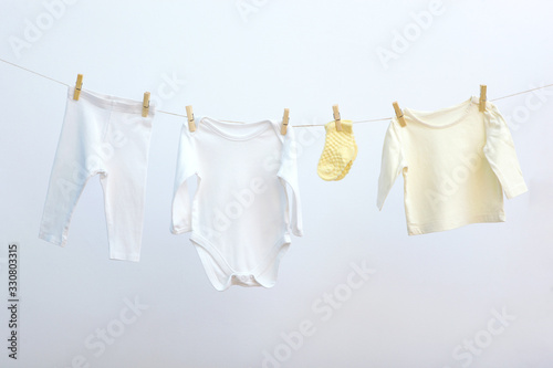 Baby clothes on a rope on a colored background. The concept of washing baby clothes. photo