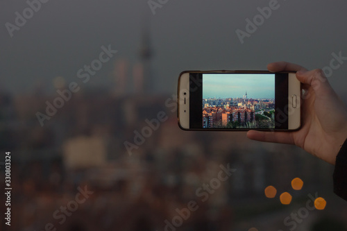 Person taking a photo with his mobile of the sunset in Madrid, Spain