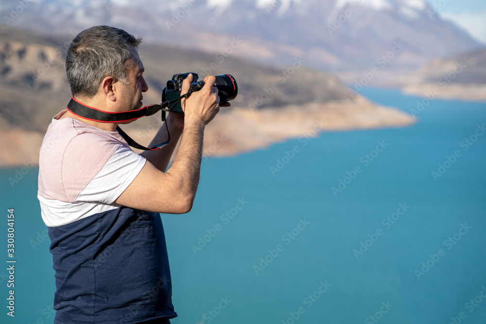 Amateur photographer holding a camera in a mountain background.. Amateur photographer holding a camera in a mountain background..