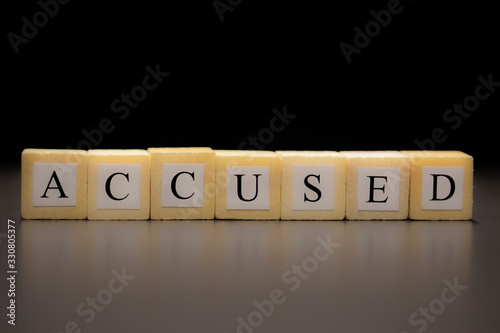 The word ACCUSED written on wooden cubes, isolated on a black background... photo