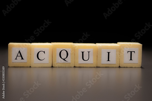 The word ACQUIT written on wooden cubes, isolated on a black background... photo