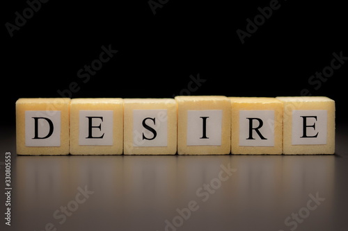 Tableau sur toile The word DESIRE written on wooden cubes, isolated on a black background