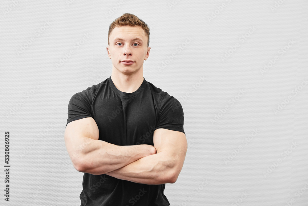 Portrait of handsome young athlete man with muscular body in black t-shirt smiling with arms crossed isolated on white background Portrait of handsome young athlete man with muscular body in black t-shirt smiling with arms crossed isolated on white background