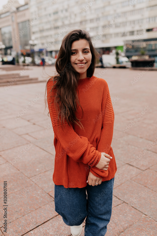 Full length image of beautiful stylish woman standing against blur city background walking and enjoying spring in the city