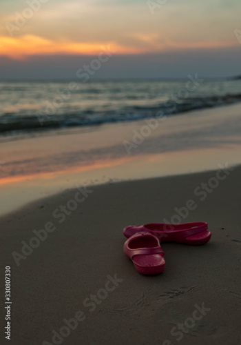 pink rubber shoes by the sea against the sunset in Thailand