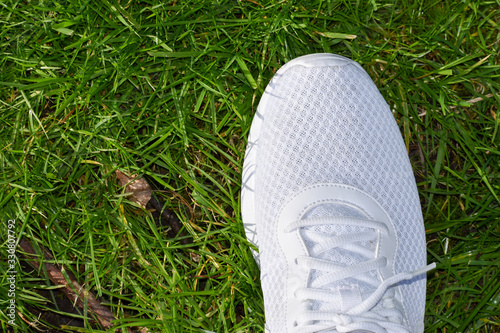 Close up of a white sports shoe, trainer, runner on grass background. Ready to run, business kick off concept