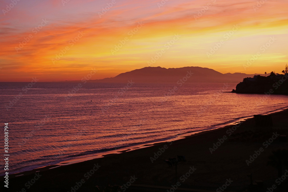 Beautiful orange red sunset in the bay of Rincon de la Victoria looking into the direction of Malaga, Spain, Europe