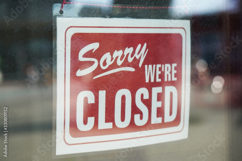 Sorry we're closed sign behind dirty glass door during corona lockdown photo