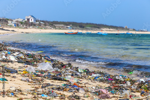 A view along a sandy beach full of plastic garbage.