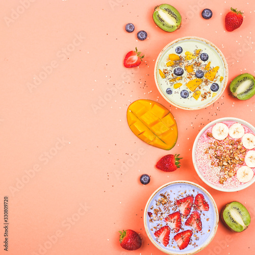 Beautiful multi-colored healthy smoothie bowls with berries and superfoods on a bright background. Summer food for detox concept. Top view, flat lay, copy space.