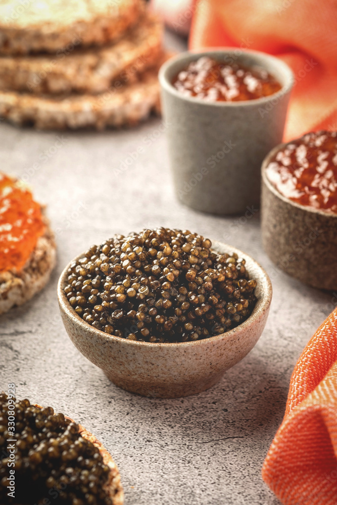 black and red caviar in bowls, snacks on a gray concrete background black and red caviar in bowls, snacks on a gray concrete background