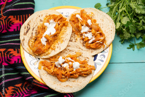Mexican chicken tinga tacos with chipotle sauce on turquoise background