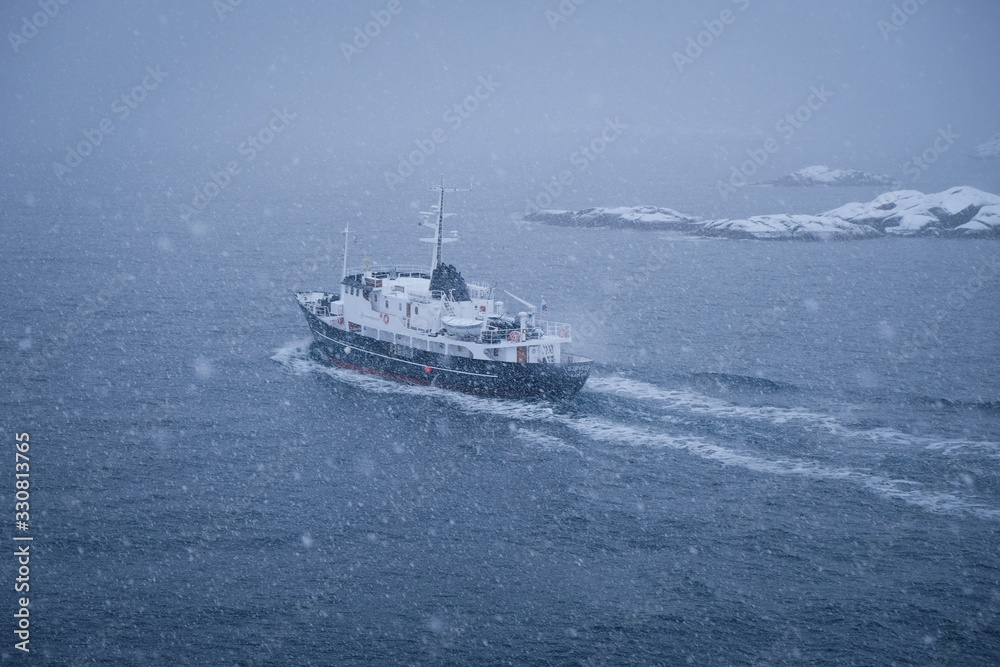 Fishing ship on the way to the ocean. Traditional cod fish season lasts during winter period. Located in beautiful lofoten islands archipelago. Fish industry behind the arctic circle. 