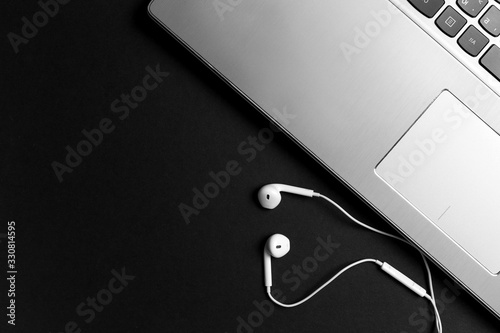 Minimal workspace with Laptop and headphones copy space on dark background. Top view. Flat lay style. Black and white photo