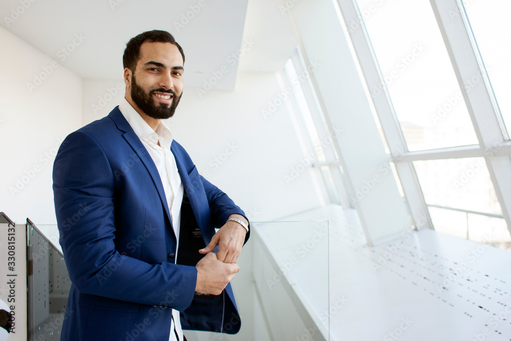 Successful handsome businessman in a blue suit at the workplace looks out the window, portrait of a manager at work Successful handsome businessman in a blue suit at the workplace looks out the window, portrait of a manager at work