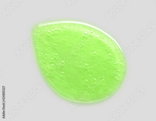 Cosmetic green liquid drop aloe vera with bubbles on grey background.