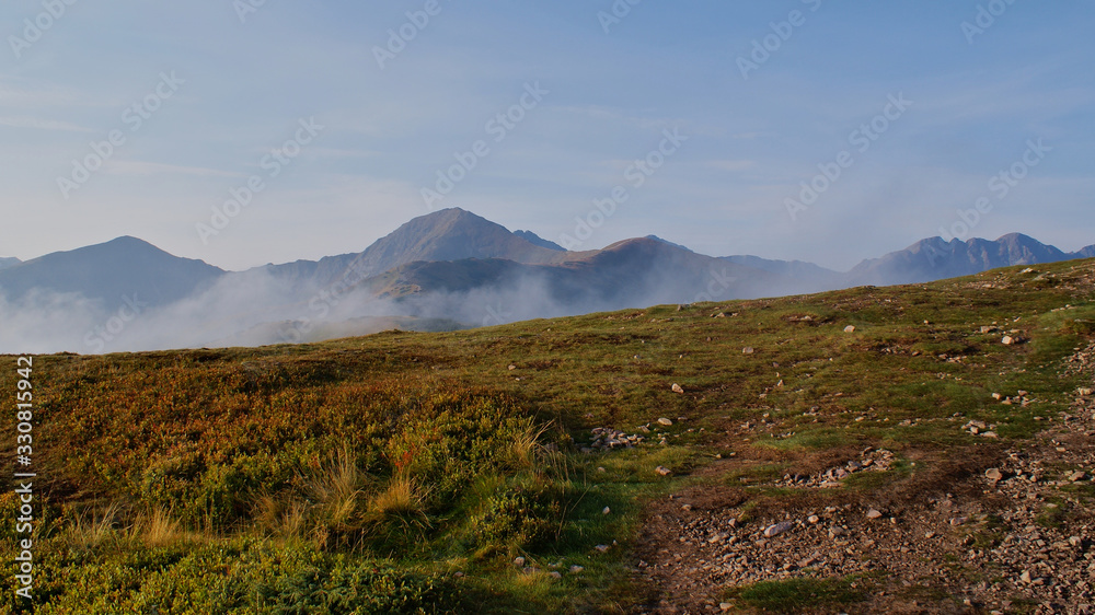 Peak of the mountains surrounded by morning fog in autumn