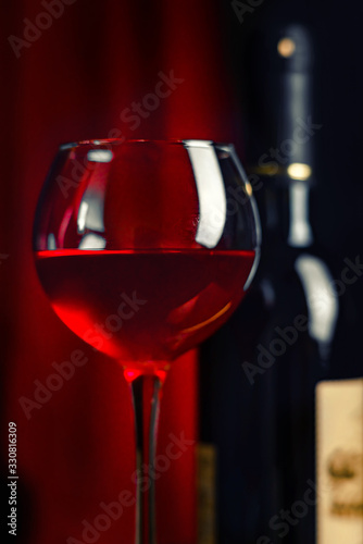 Wine. A glass and a bottle of red wine.. Red wine on a dark red background