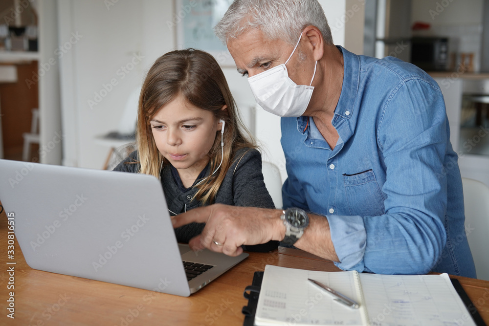 Fototapeta premium Father and child at home working on laptop, telework and home-schooling