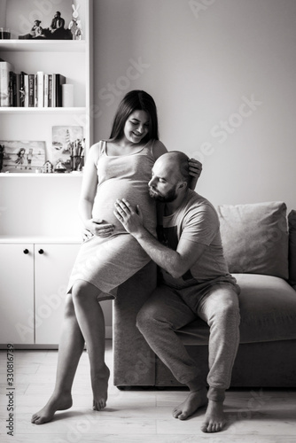 Pregnancy. Young couple waiting for baby. Wonderful expectant parents cuddle in their apartment awaiting birth