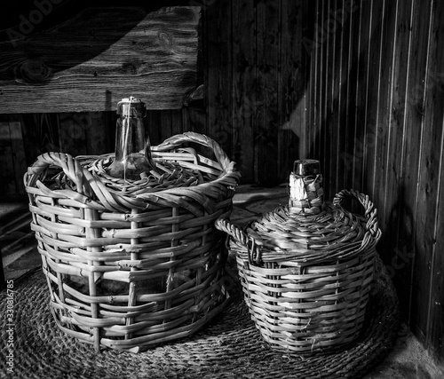 Dos antiguas garrafas de vino de cristal y mimbre en el suelo de la bodega