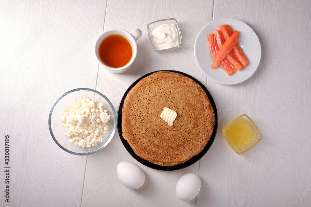 Plate with pancakes on a white table, honey, sour cream
