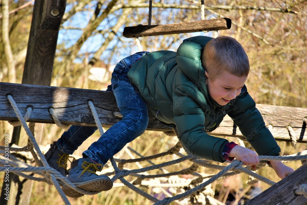 boy on the playground climbs the rope boy on the playground climbs the rope