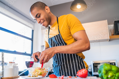 Young latin man preparing food at home.
