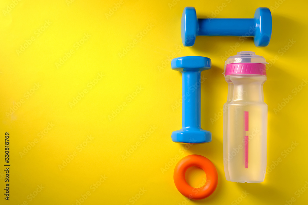 Water bottle, dumbbells, sneakers, sports symbols, on yellow background, place for an inscription Water bottle, dumbbells, sneakers, sports symbols, on yellow background, place for an inscription