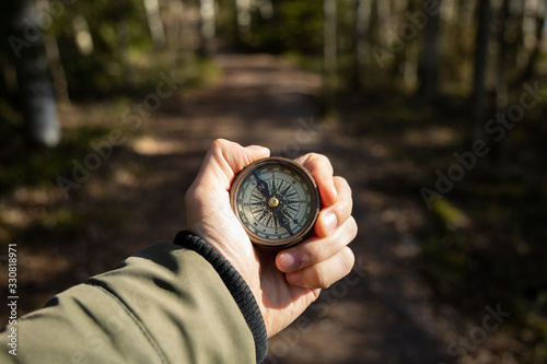 Traveler man searching direction with a compass in spring forest. Find the path concept.
