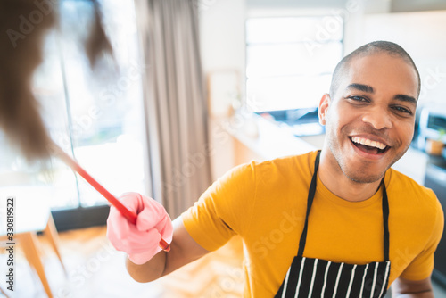 Photography Young latin man dusting his new house.