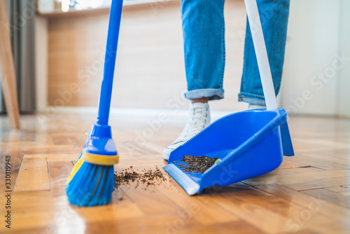 Latin man sweeping wooden floor with broom at home. photo