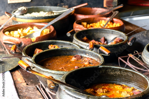 Typical Brazilian foods placed in clay pots and on a metal plate of a traditional wood stove