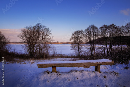 An empty bench in front of the Breite Luzin in the Feldberg lake district photo