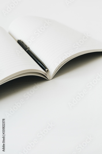 Open notebook with pen on white background.