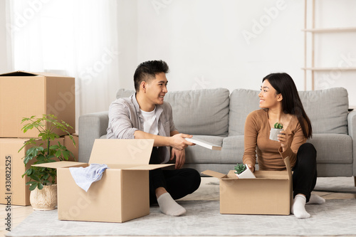 Asian man and woman sitting on the floor with boxes