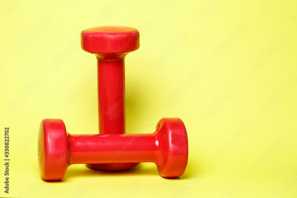 red sports dumbbells on a yellow background