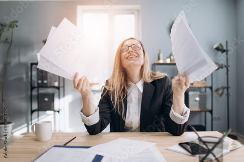 Mature blonde woman in business suit and eyeglasses feeling stress because of long paper work at office center. Concept of business and working process.