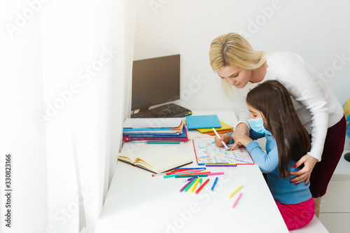 mother and daughter in protective mask do homework at distance home schooling, quarantine