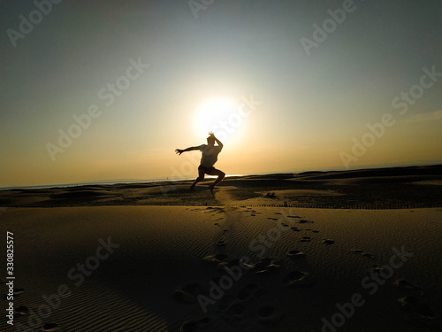 A man jumping in the sand on the beach with a sunset backgroundman jumping on the beach with a sunset in the background